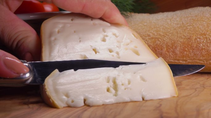 刀子切下一块柔软的羊奶酪