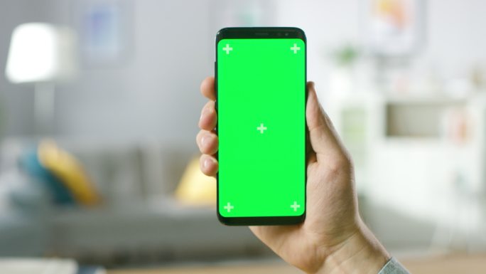男子手持带有绿色模拟屏幕的现代智能手机