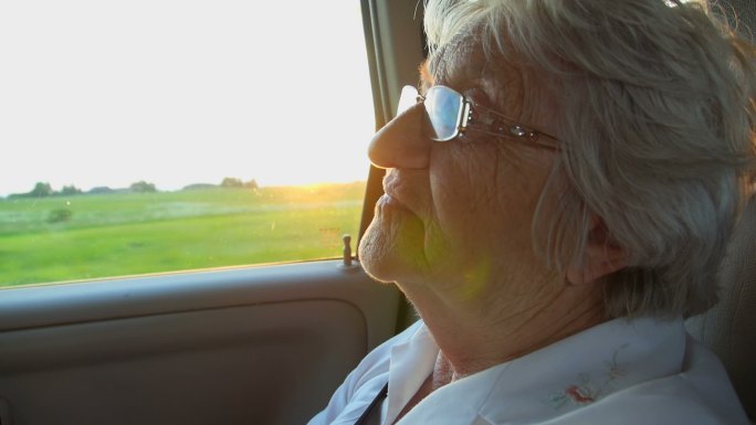 夕阳下，车里的老妇女在微笑