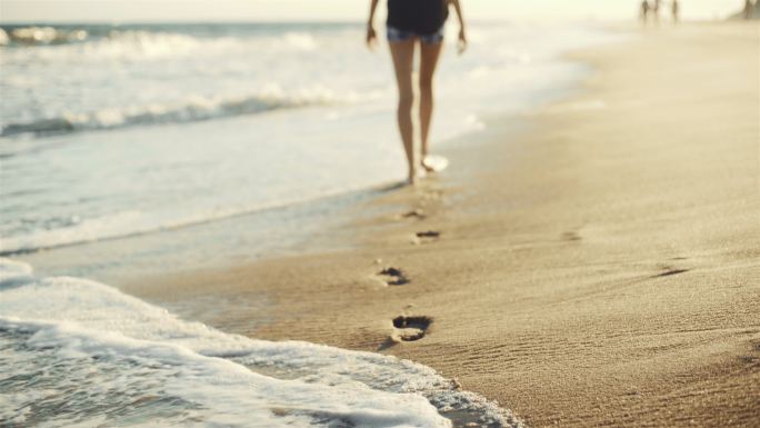 女孩走在沙滩上留下脚印