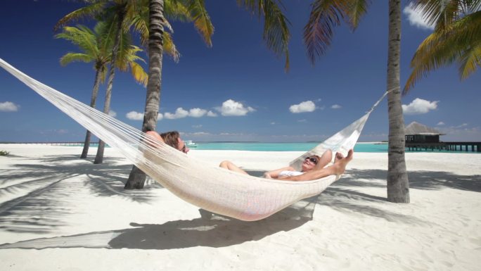 情侣们在热带海滩的吊床上放松