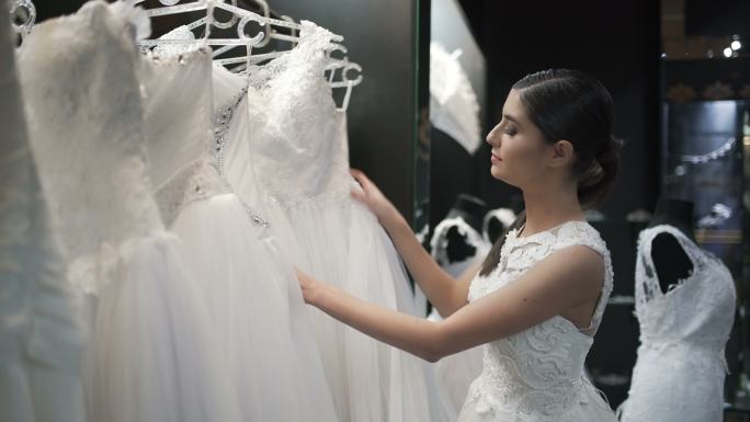 美丽的年轻女子在婚礼店寻找心仪的婚纱。