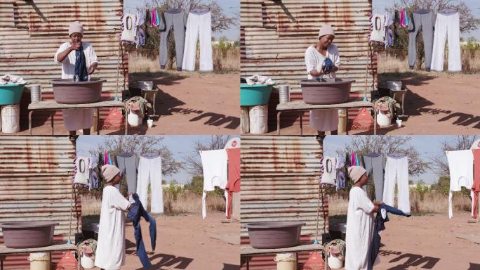 妇女在铁皮棚屋前的桶里洗衣服