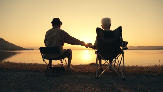 老年夫妇在湖边欣赏日落美景