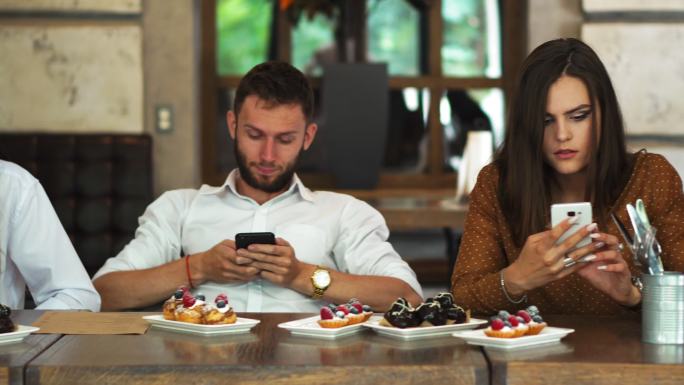 一群朋友坐在餐厅里，玩着各自的手机。