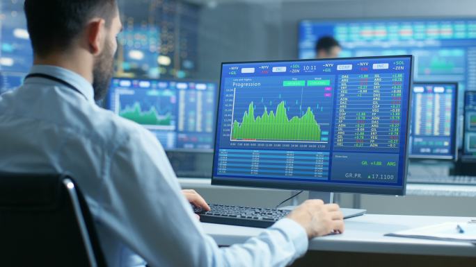 股票市场交易者在电脑上工作的肩上视图