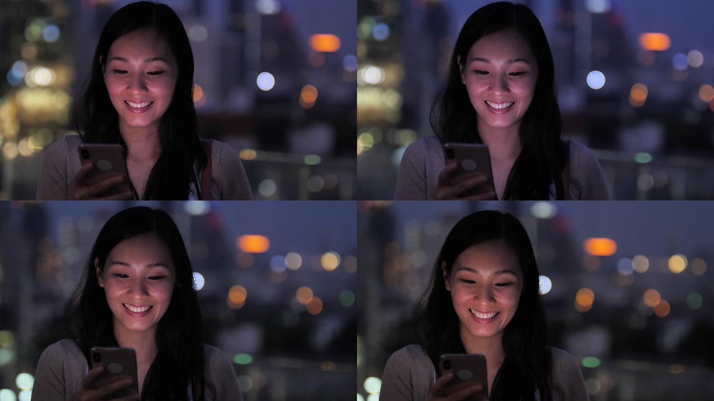 美女在城市的夜里使用智能手机