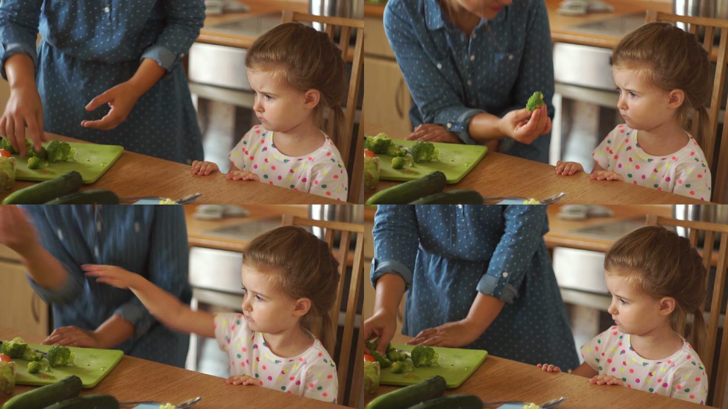 小女孩和妈妈在厨房里。妈妈把花椰菜给了女儿