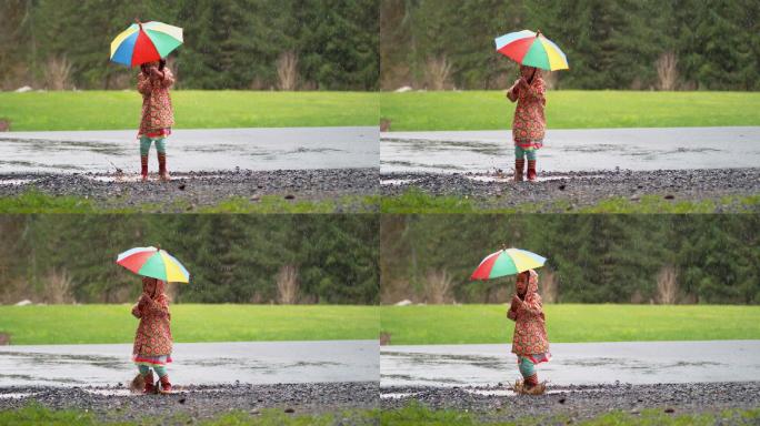 带着雨伞的小女孩在雨中嬉戏
