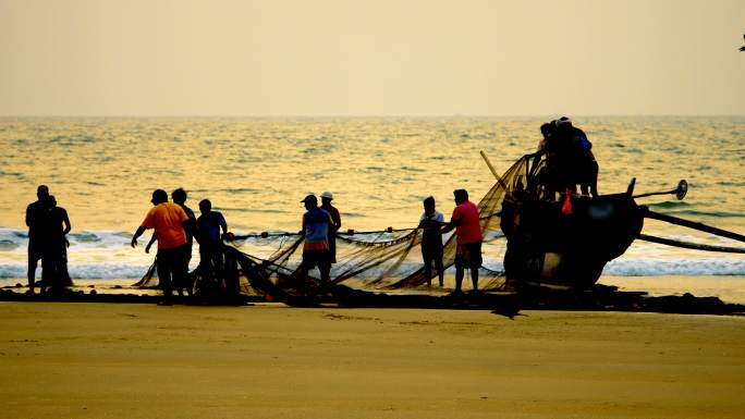 渔民在渔船上铺设渔网的剪影