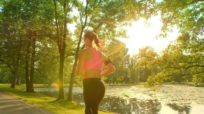 一个在阳光下沿着湖边奔跑的女人