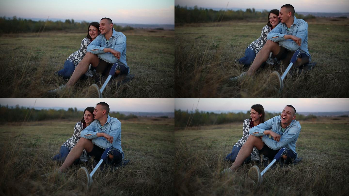 日落时的坐在草地的夫妻。有假腿的男人。
