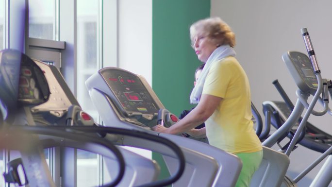 老奶奶在健身房的跑步机上训练