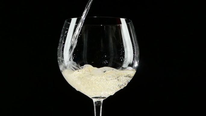 将白葡萄酒倒入一杯黑底酒中。