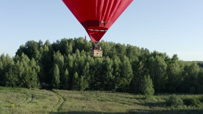 心脏形状的热气球在绿色田野和夏季森林上空飞行