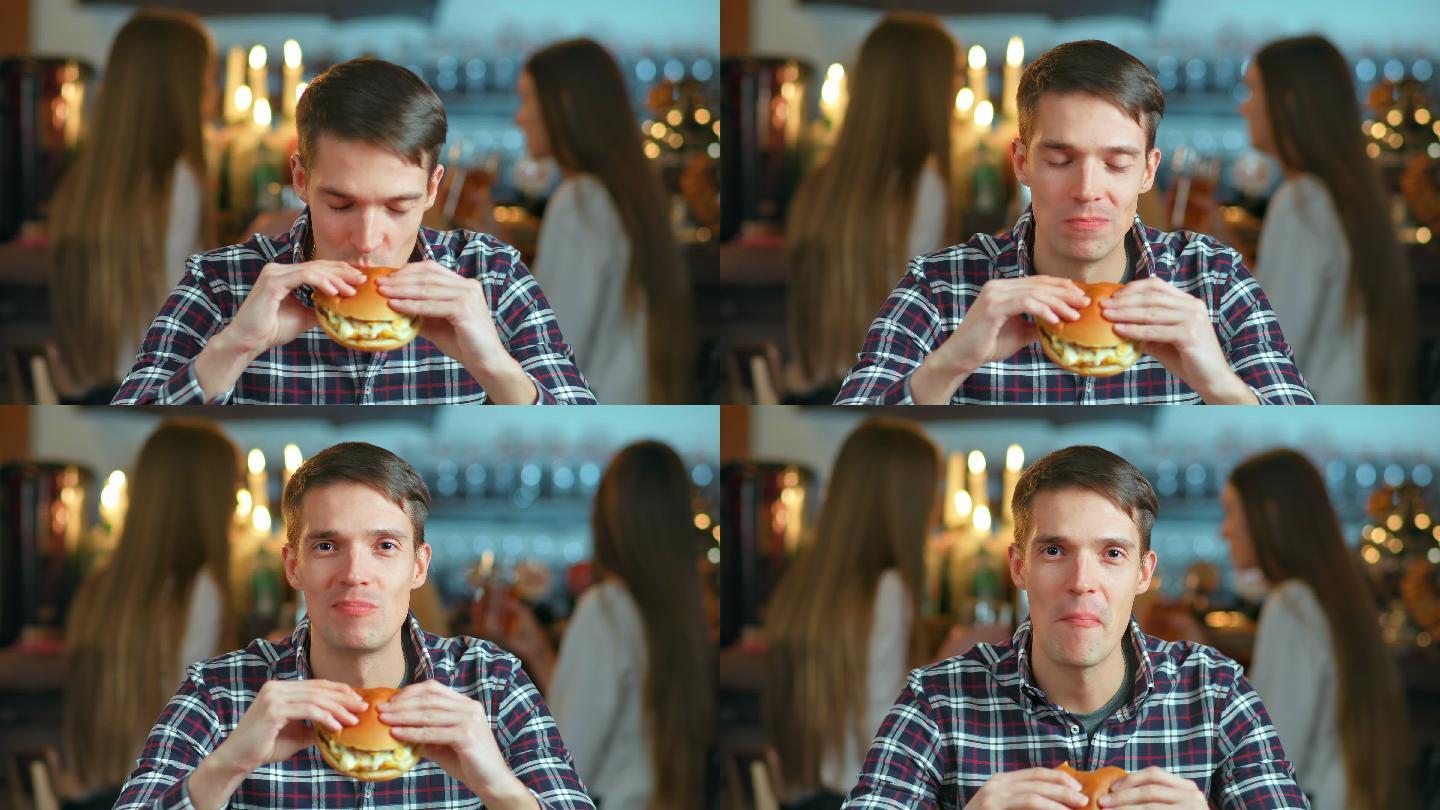 餐馆里的男人吃着汉堡包，微笑着