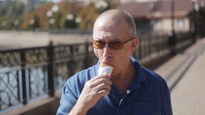 镜头前，一位老人在吃冰淇淋的照片