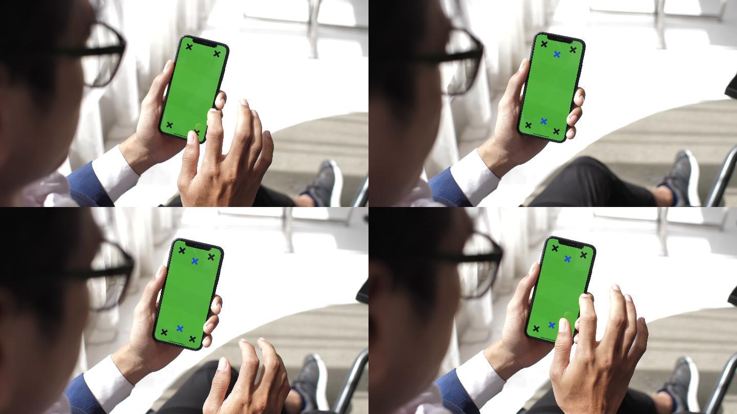 男子手持绿色屏幕手机