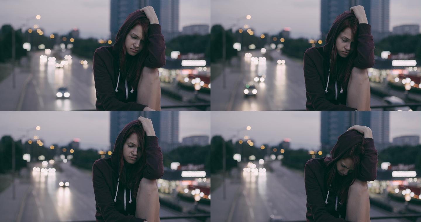 黄昏时独自坐在桥上沮丧的女孩。