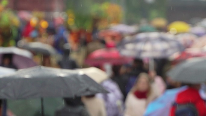 人们在繁忙的购物街上撑着雨伞，以防下雨。