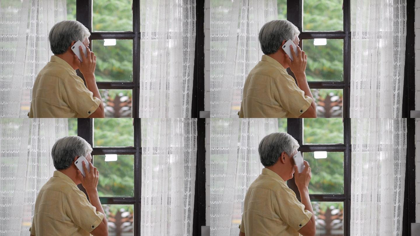 一位男士在家里靠窗边愉快地用智能手机交谈