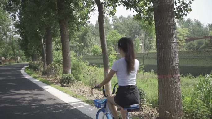 在风景优美的小路上 美女骑行共享单车
