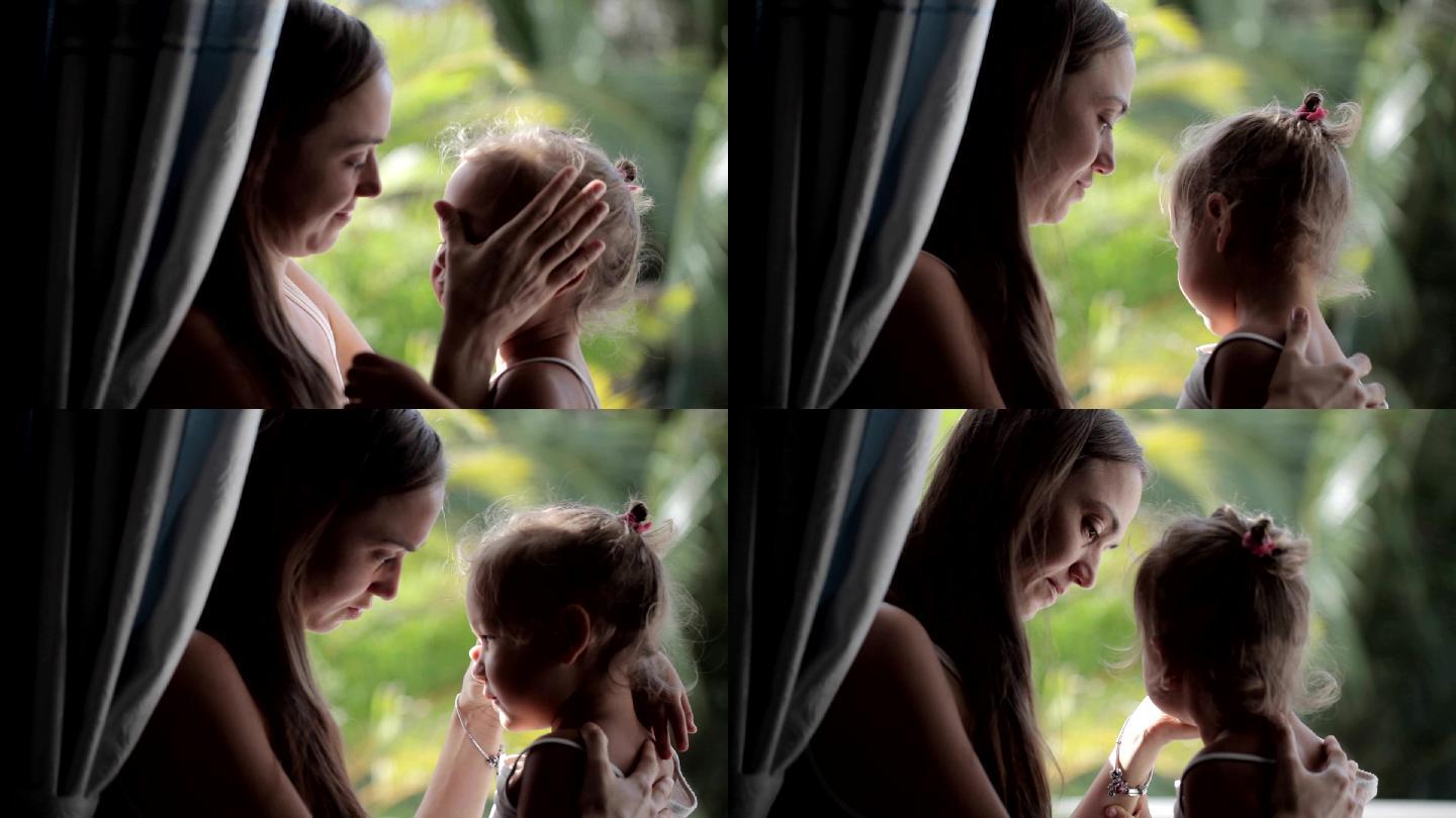 美丽的母亲抚慰和拥抱哭泣的女婴。