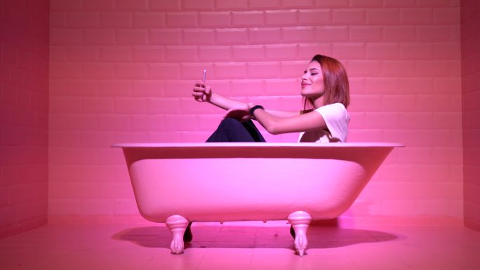 在粉色浴缸里自拍的女人