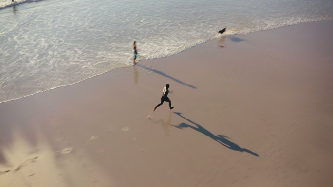 一个英俊的年轻运动员白天沿着海滩疾跑