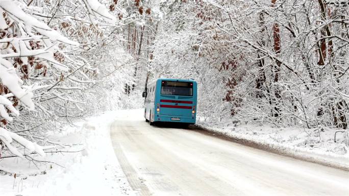 公共汽车沿着雪路穿过森林。