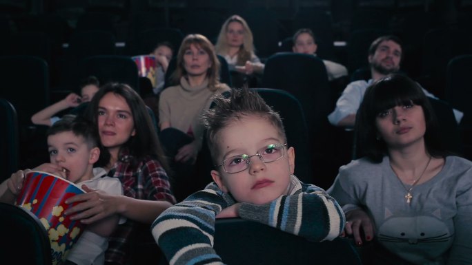 戴眼镜的男孩在电影院看电影