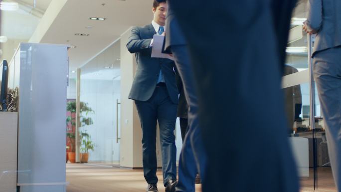 商业人士穿过公司大楼走廊的低角度照片。