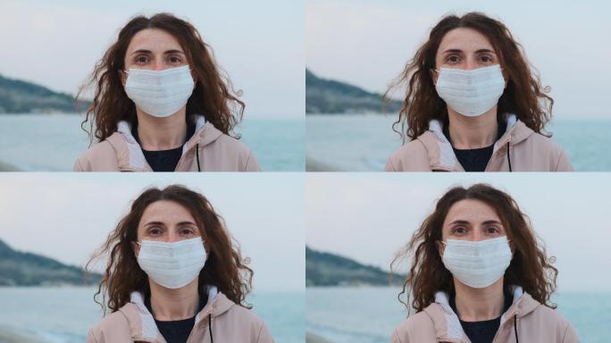 一名妇女戴着医用口罩站在海边