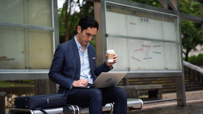带助听器的男子在公共汽车站使用笔记本电脑