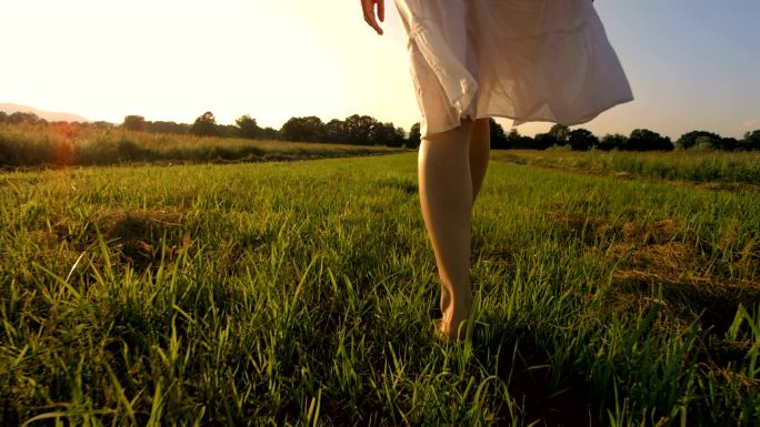 赤脚在草地上行走的一个年轻女子