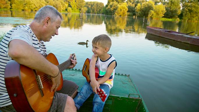和爷爷一起弹吉他的小男孩