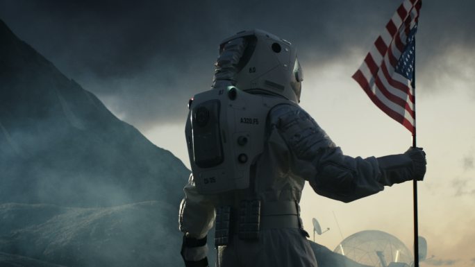 宇航员在黑暗的外星行星上举着美国国旗行走。
