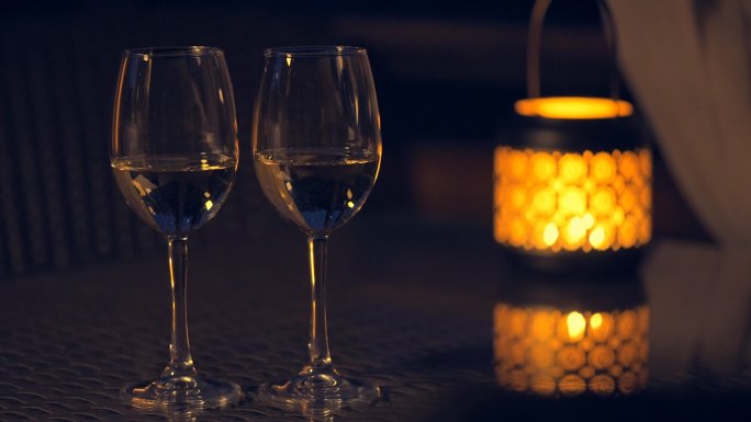 两个白葡萄酒酒杯，桌上点着蜡烛。