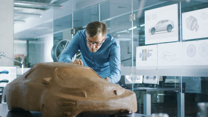 汽车设计在橡皮泥上雕刻原型汽车模型。