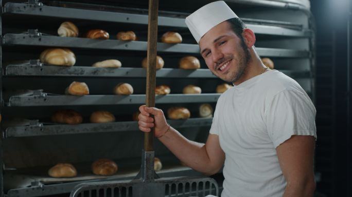 面包师从烤箱里拿出热面包的慢镜头特写。