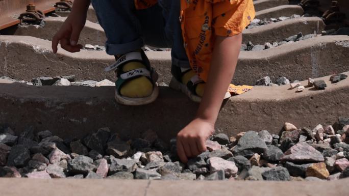 小孩铁路上玩石子