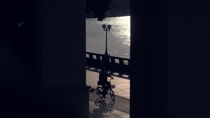 江边大桥下骑自行车经过的行人