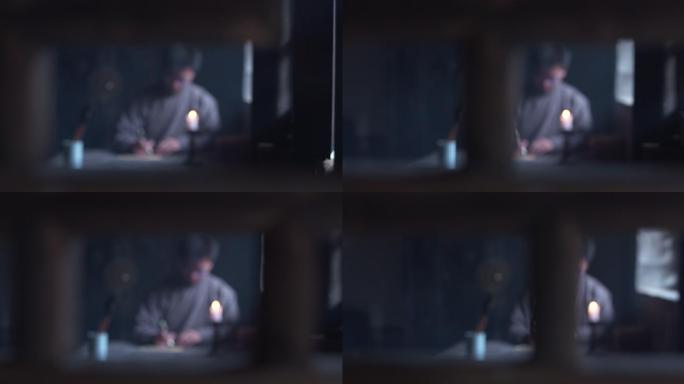 情景再现穿长袍的男人坐在桌子前写字正面