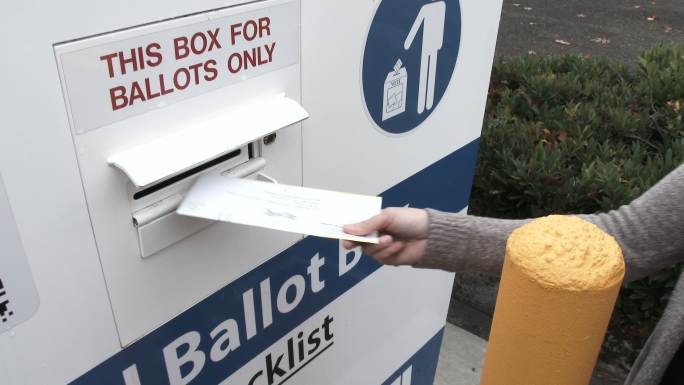 投票人在选举日将选票送到投票箱