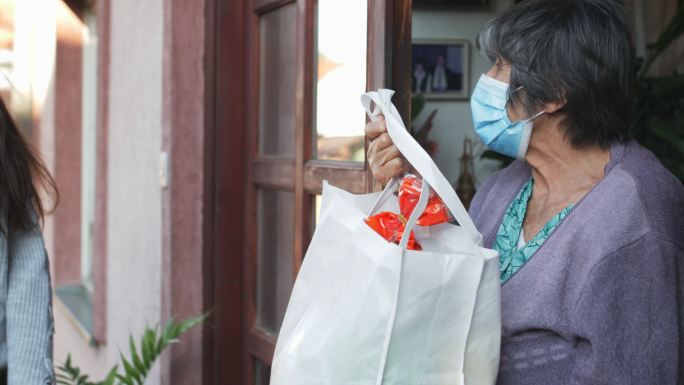 志愿者向一位年长女性运送食品杂货