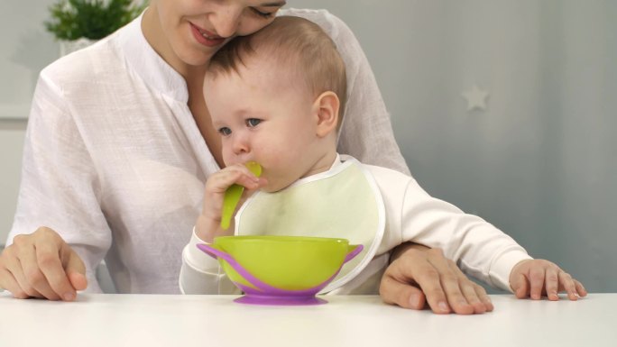 母亲帮助婴儿独自吃饭