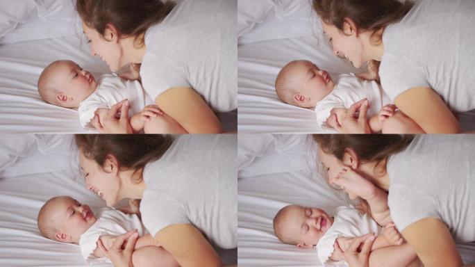 年轻妈妈抱着可爱的女婴躺在床上