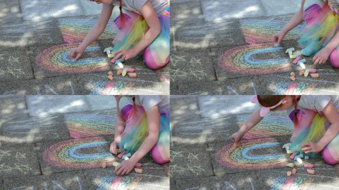 女孩坐在屋外的小路上用粉笔画彩虹