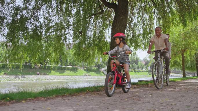 一家三口子公园里骑着自行车