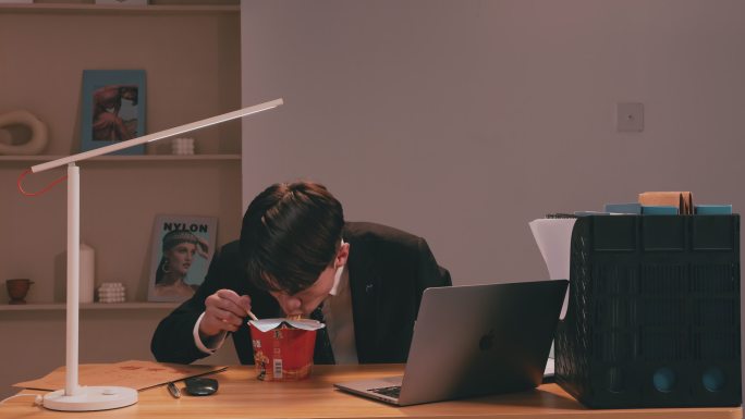 西装商务男子边工作边吃泡面颓废